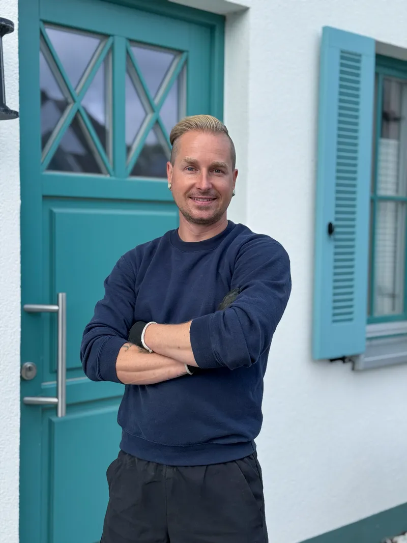 Martin Zühl, Inhaber von Zühl Hausmeister- & Handwerksservice Stralsund, lächelt vor einem Hauseingang